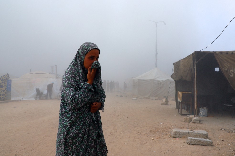 Palestina em campo de refugiados cobre o rosto após bombardeio israelense derrubar prédio na Cidade de Gaza, na Faixa de Gaza, em 5 de setembro de 2025. — Foto: REUTERS/Ebrahim Hajjaj