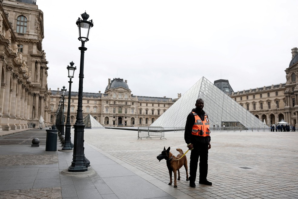 Segurança com cão de guarda próximo à Pirâmide de vidro do Museu do Louvre após roubo de joias em 20 de outubro de 2025. — Foto: Benoit Tessier/Reuters