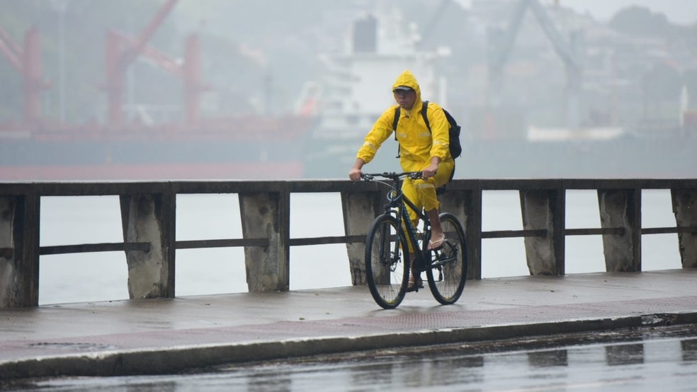 Pessoa de capa de chuva durante tempo chuvoso em Vitória, no ES — Foto: Ricardo Medeiros/Rede Gazeta