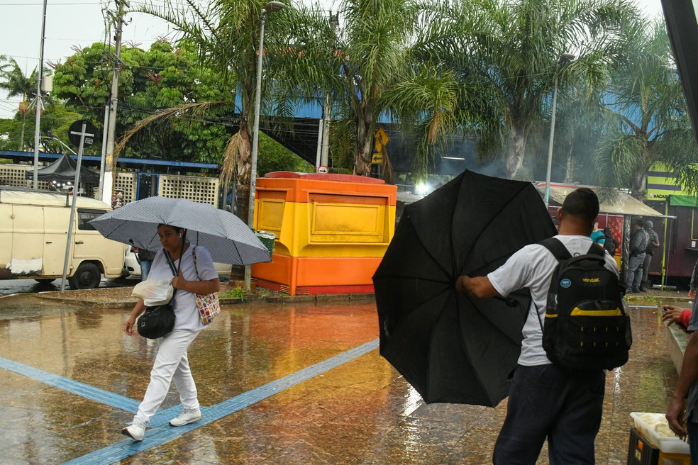 Pedestres se protegem da chuva na região de São Mateus, na zona leste de São Paulo (SP). — Foto: EDI SOUSA/ATO PRESS/ESTADÃO CONTEÚDO