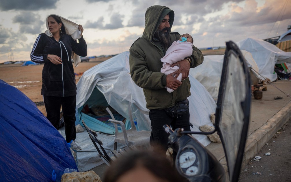 Ahmad Al Saghir, 38, segura seu filho de dois meses, Adam Al Saghir, do lado de fora de sua tenda familiar, em um acampamento temporário para pessoas deslocadas em Beirute, no Líbano, 30 de março de 2026. — Foto: Adnan Abidi/Reuters