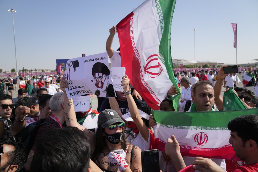 Apoiadores agitam bandeiras iranianas e uma mulher segura uma placa com os dizeres "Liberdade para o Irã. Não à República Islâmica" — Foto: Jin-Man Lee/AP